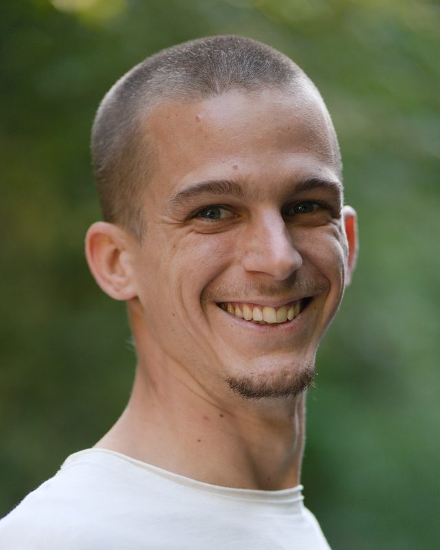 Arnaud Martig, souriant, en t-shirt blanc devant un fond de verdure